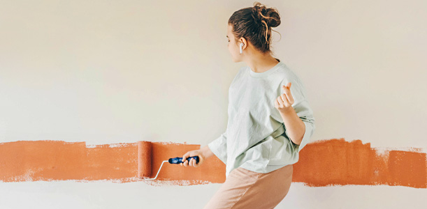 Woman dancing while painting a wall